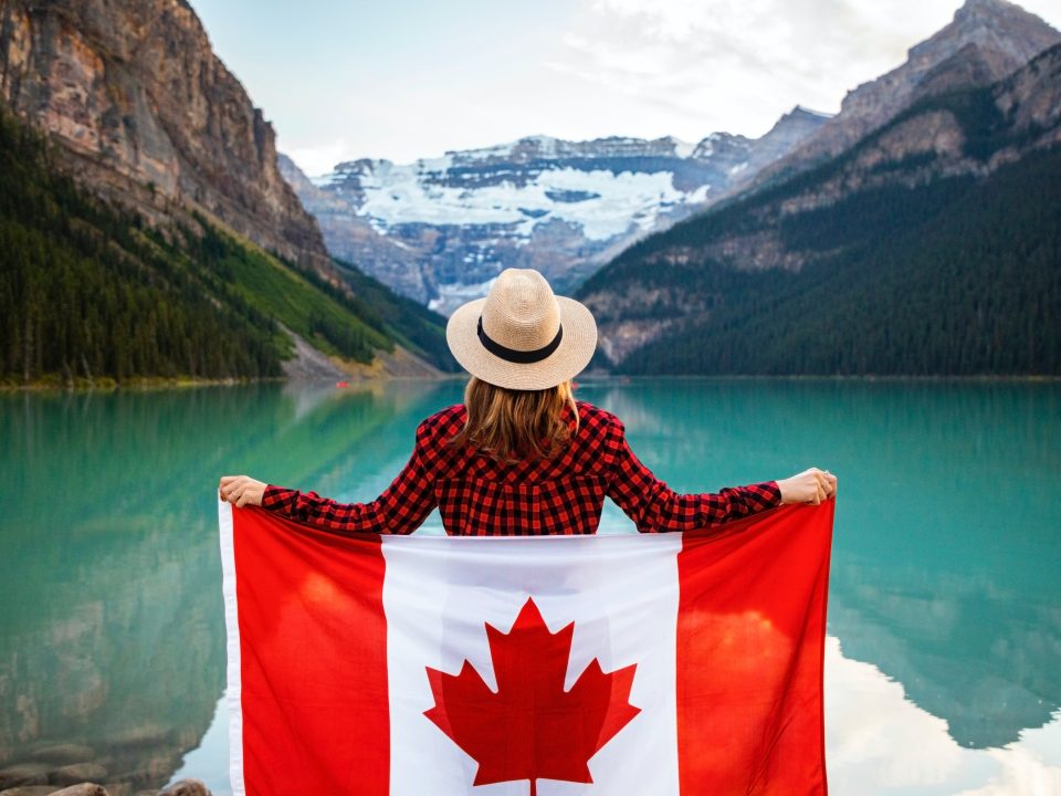 Girl on a lake somewhere in Alberta, holding a Canadian flag